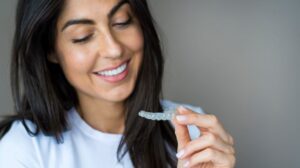 Smiling woman looking at her clear aligner